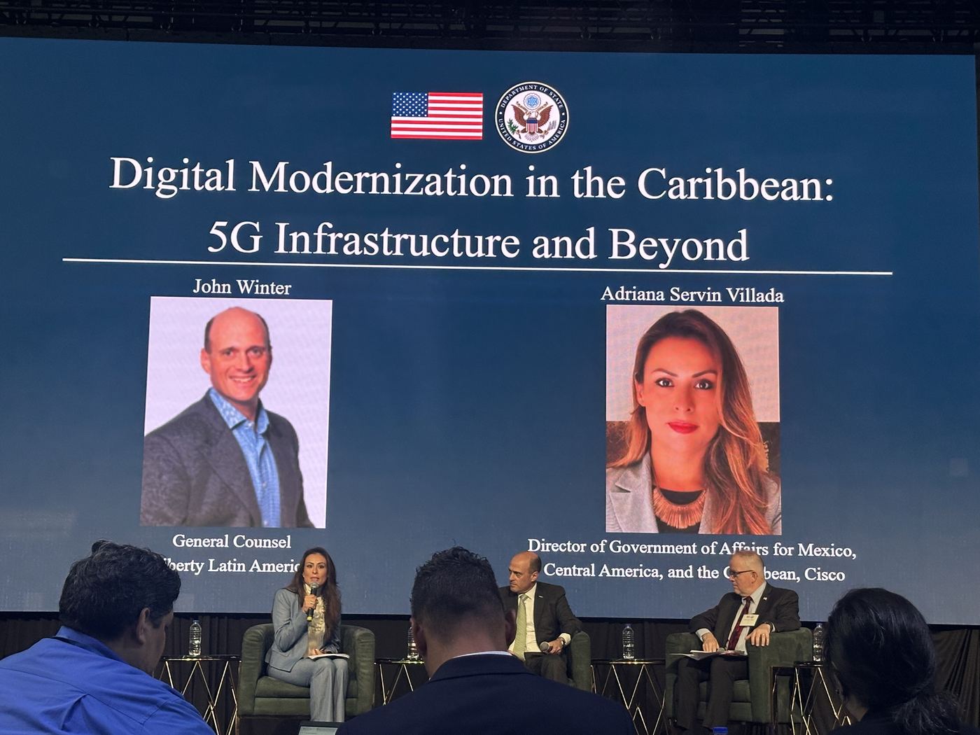 Panel on stage beneath a slide reading Digital Modernization in the Caribbean