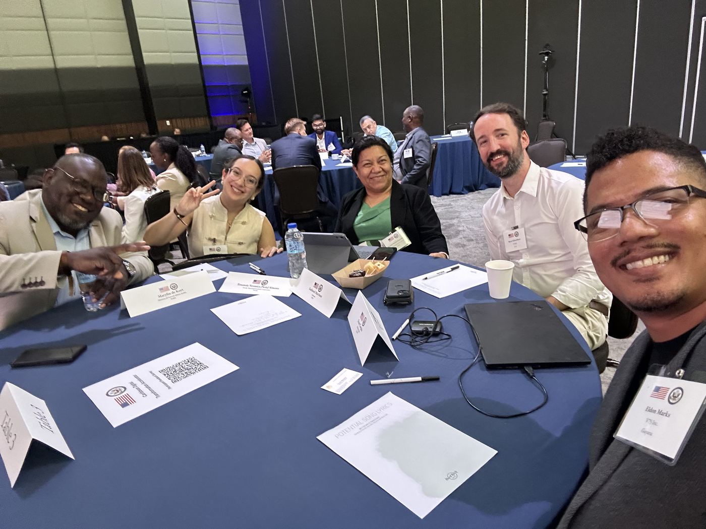 Delegates around a working table with name tents, laptops and notes